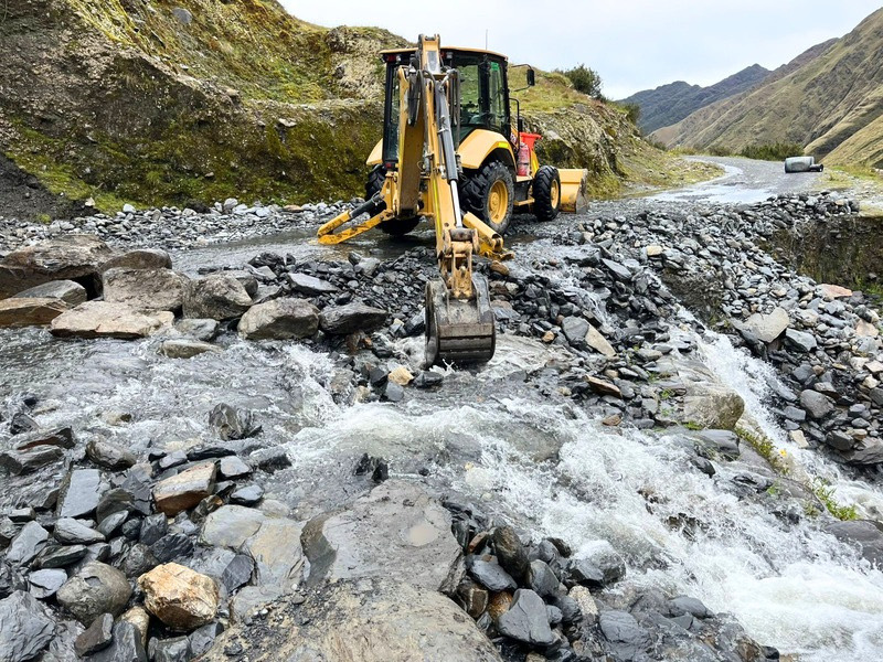 Retroexcavadora CAT cruzando un río durante apertura de carretera
