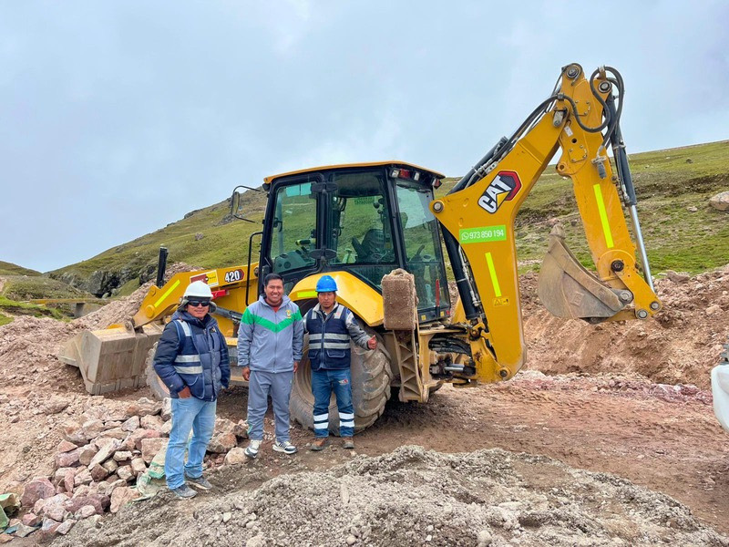 Equipo de Corporación Guzman Sur junto a retroexcavadora en obra, Corani - Puno